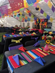 tables set up with colorful table cloths and place settings under a tented area