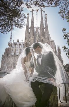 a bride and groom sitting on steps in front of a cathedral