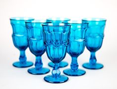 blue wine glasses lined up on a white surface