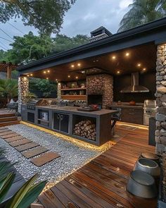 an outdoor kitchen with wood flooring and stone walls is lit up by string lights