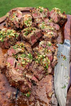 a wooden platter filled with sliced up steak