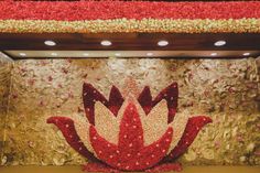 a large red and white flower arrangement in front of a gold wall with flowers on it