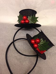 two hats with holly leaves and red berries on them are sitting on a black headband