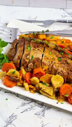 a white plate topped with meat and veggies on top of a marble counter