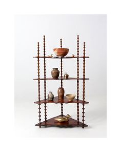 three tiered shelving unit with bowls and vases on each shelf in front of a white background