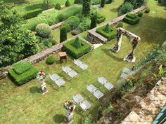 an aerial view of a formal garden with lawn chairs and flowers in the center, surrounded by greenery