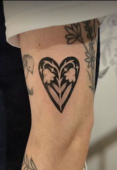 a woman's leg with a heart shaped tattoo on the lower part of her arm