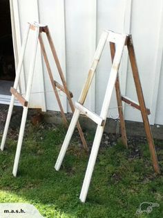 two wooden ladders leaning against a white wall in the grass next to a door