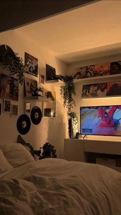 a bed with white sheets and pillows in front of a flat screen tv mounted on the wall