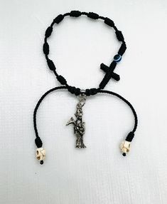 Hand made Santa Muerte black woven knots denary bracelet woven knot crucifix and decorated with blue/black  evil eye bead. Material: Black nylon string #18, 9 charm metal Santa Muerte 3D length 3cm blue/black evil eye 6mm stainless steel bead 6mm white skull 6mm Adjustable Handmade Black Rosary Bracelet, Gothic Black Adjustable Beaded Bracelets, Gothic Black Beaded Adjustable Bracelet, Gothic Adjustable Black Beaded Bracelets, Adjustable Black Cross Bracelet, Bohemian Cross Beaded Bracelets Adjustable, Bohemian Beaded Cross Bracelets With Adjustable Fit, Adjustable Crucifix Spiritual Bracelet, Adjustable Cross Beaded Bohemian Bracelets