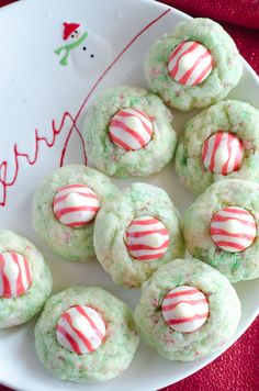 green and white cookies with candy canes on a red tablecloth next to a plate