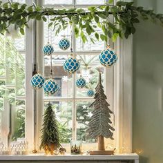 christmas decorations hanging from a window sill in front of a tree and fireplace mantel