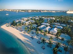 an aerial view of a beach resort in the middle of the ocean with boats and palm trees