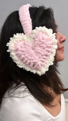 a woman wearing a pink and white crocheted heart shaped hair clip in front of her face