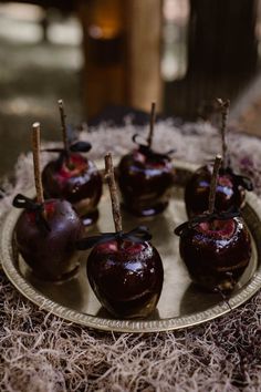 chocolate covered apples sitting on a plate with sticks sticking out of it's centers