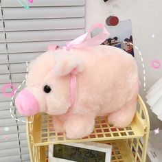 a pink pig stuffed animal sitting on top of a shelf next to a digital clock