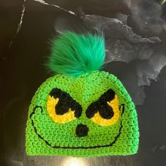 a crocheted hat with green hair and eyes