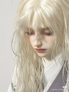 a white doll with long blonde hair wearing a sweater