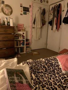 a bedroom with leopard print bedding and clothes hanging on the closet wall above it