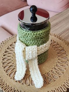 a crocheted pot holder with a lid and scarf on top of a table