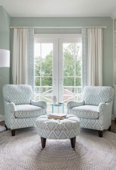 a living room with two chairs and a ottoman