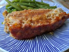 meatloaf and green beans are on a plate with blue striped sauce in the center