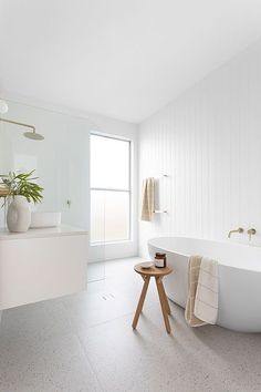 a white bathroom with a large tub, sink and mirror on the wall next to it