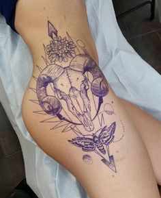 a tattoo on the side of a woman's thigh with an animal skull and flowers