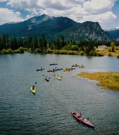 several kayakers are on the water with mountains in the background