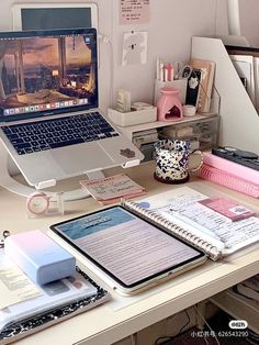 an open laptop computer sitting on top of a desk next to a pile of books