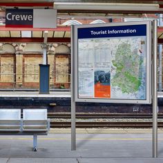 a bench sitting in front of a train station next to a sign that says tourist information