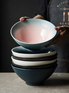 a person holding a bowl in front of four bowls stacked on top of each other