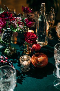 a table topped with lots of glasses and vases filled with different types of flowers