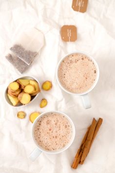 two mugs filled with hot chocolate and cinnamon on top of a white table cloth