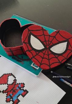 a paper box with an image of spiderman on it next to markers and pens