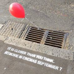 a red balloon floating over a manhole cover