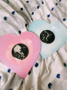 two heart shaped plates sitting on top of a bed next to blue and pink sheets