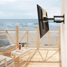 a flat screen tv mounted to the side of a wall next to a chair and table