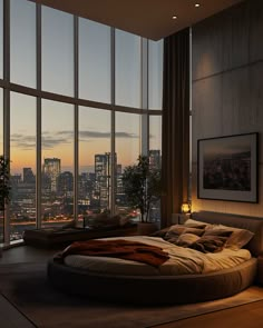 a large bed sitting in the middle of a bedroom next to tall windows with city lights on them