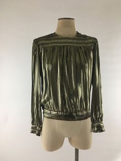 "Fabulous Lloyd Williams very lightweight 1980's black & gold lamé striped pleated blouse with puffed sleeves and slight bishop cuffs. Covered buttons are on the waist, cuffs and shoulder and blouse has shoulder pads that may easily be removed if so desired. The black rayon stripes are sheer and the gold lamé is more opaque. Blouse is in excellent vintage condition. Labeled a size 10, though please do check the measurements 85% rayon 15% metallic thread Shoulders 15\" across Chest 42\" Waist Striped Long Sleeve Party Top, Striped Long Sleeve Party Blouse, Classic Gold Tops For Party, Striped Tops For Fall Party, Classic Gold Tops For Spring, Vintage Gold Top For Formal Occasions, Vintage Gold Long Sleeve Blouse, Vintage Gold Blouse For Party, Gold Long Sleeve Vintage Blouse