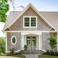 a gray house with white trim and two large windows on the front door is shown