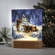 a christmas scene with bears in the snow on a wooden stand next to pine cones