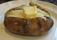 a baked potato with butter on it sitting on a white plate