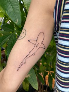 a person with a tattoo on their arm holding a small airplane in the air,