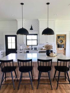 a kitchen with black chairs and white counter tops in front of a large center island