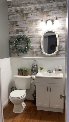 a white toilet sitting next to a sink in a bathroom under a wooden paneled wall