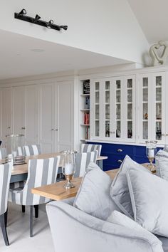 a living room filled with furniture next to a dining table and white cupboards in a kitchen