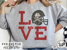 a woman sitting on a couch wearing a sweatshirt that says love with a football helmet