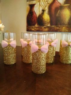 gold glitter wine glasses with pink bows are sitting on a table in front of a painting