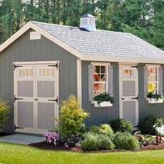 a small shed with windows and flowers in the yard